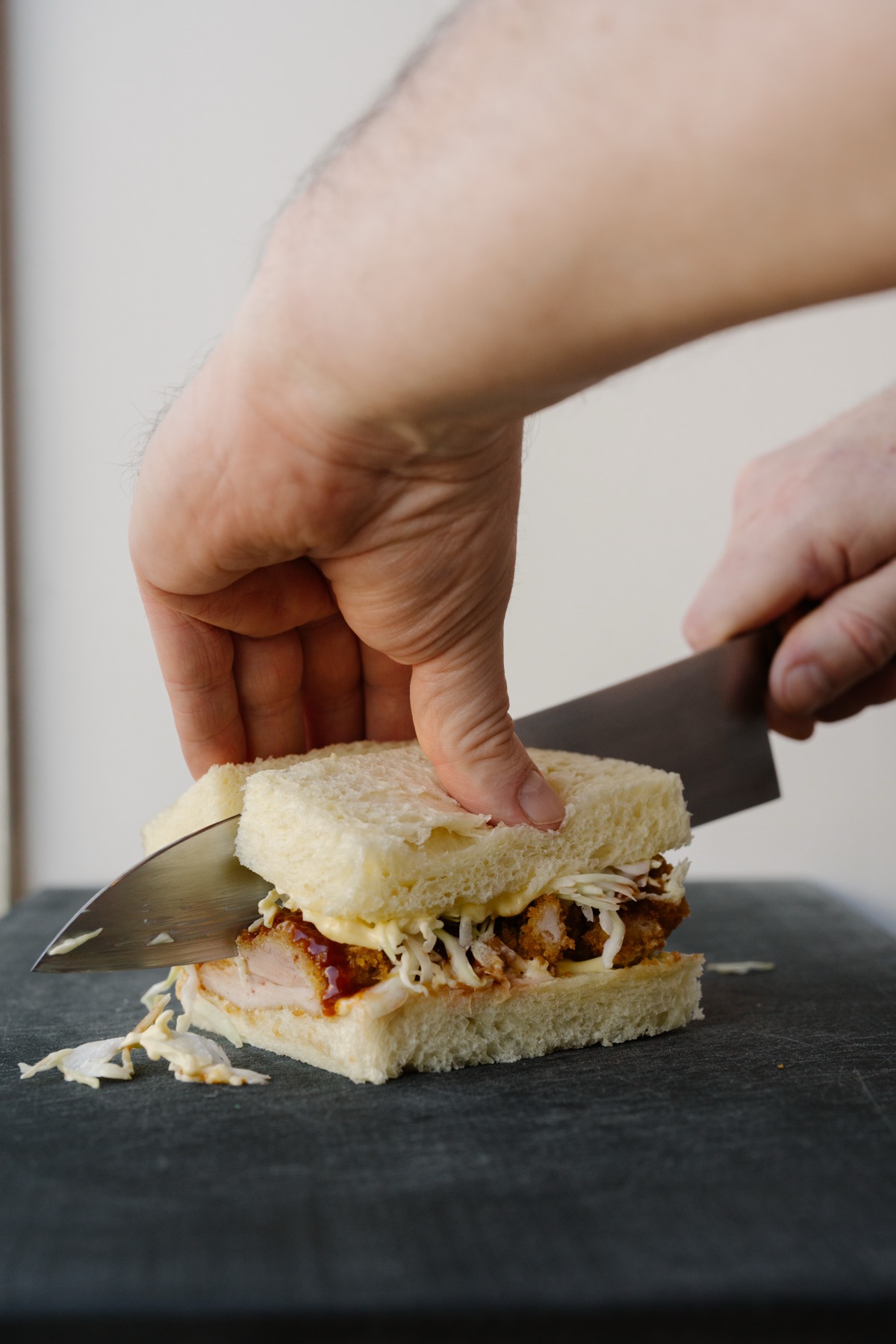 Slicing a finished sando in half with a chef's knife